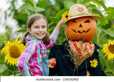 Scarecrow and happy girl  in the garden - Autumn harvests, Thanksgiving vegetable, Halloween