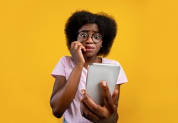 Scared African American Woman Holding Mobile Phone Seeing Bad News, Photos Or Message And Looking At Camera Over Yellow Background. Human Reaction, Expression