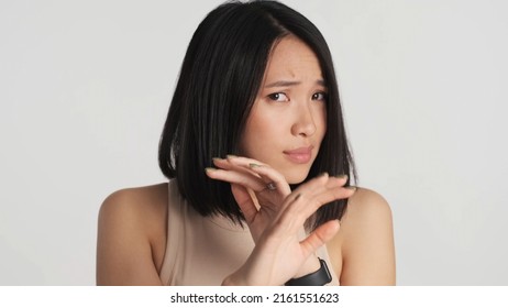 Scared Asian Woman Hiding Face With Hands Afraid Of Something Over White Background. Human And Phobia Concept