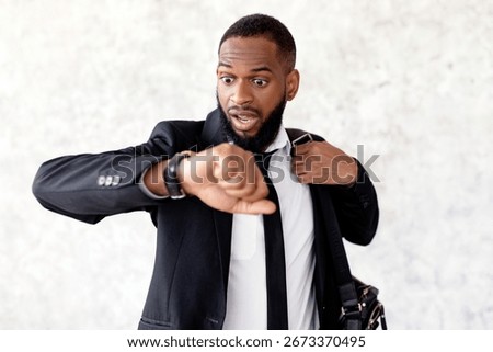 Scared black man is late for work looking at watch