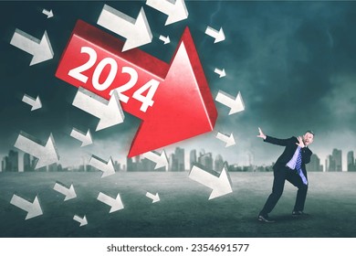 Scared businessman attacked by arrows with 2024 numbers while standing in cloudy sky background