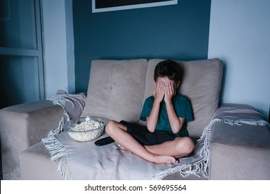 Scared Child Watching Scary Movie On Tv, Sitting On The Couch At Night