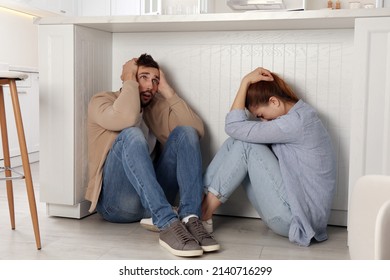 Scared Couple Hiding Under Table In Kitchen During Earthquake