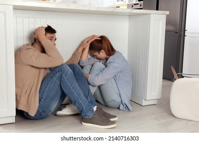 Scared Couple Hiding Under Table In Kitchen During Earthquake