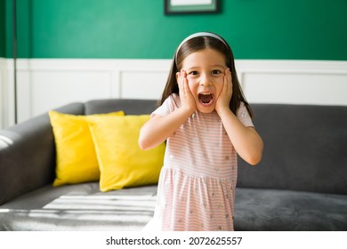 Scared Elementary Kid Screaming And Feeling Afraid After Watching A Scary Movie. Angry 5 Year Old Girl Throwing A Tantrum At Home