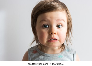 Scared Emotional Toddler Child With Big Eyes On Neutral Background Closeup