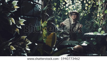 Scared explorer finding ancient ruins in the forest, she is holding a machete and walking