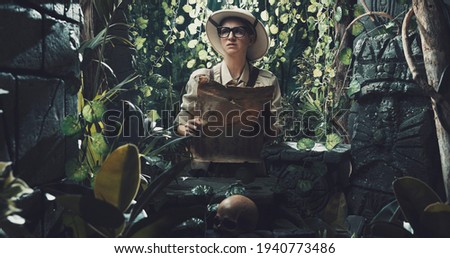 Scared explorer lost in the jungle: she is holding a map and looking at some ancient ruins