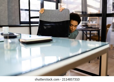 Scared Female Hiding Under Desk In Office