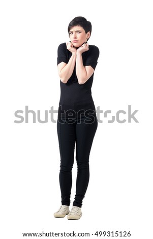 Scared freezing cold woman in turtle neck t-shirt posing at camera. Full body length portrait isolated over white studio background.