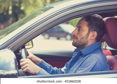 scared funny looking young man driver in the car. Human emotion face expression. Side window view of inexperienced anxious motorist  