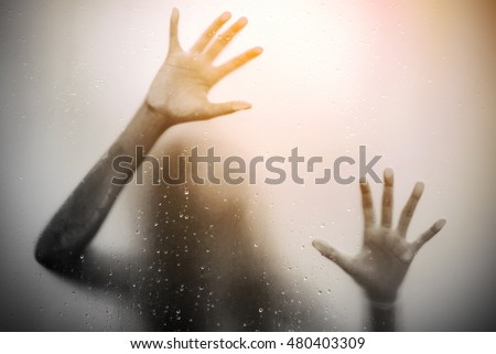 Scared girl hand behind glass door with lens flares