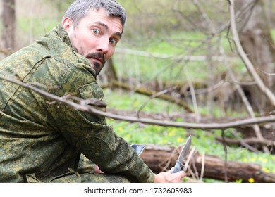 scared hunter in camouflage with a knife and phone