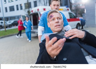 Scared Injured Man With Wound On Head Lying On Ambulance Stretcher