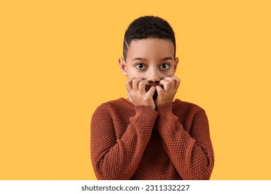 Scared little African-American boy on yellow background - Shutterstock ID 2311332227