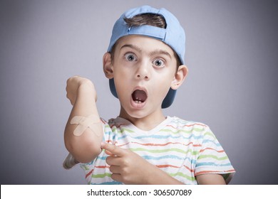 Scared little boy showing band aid in hand