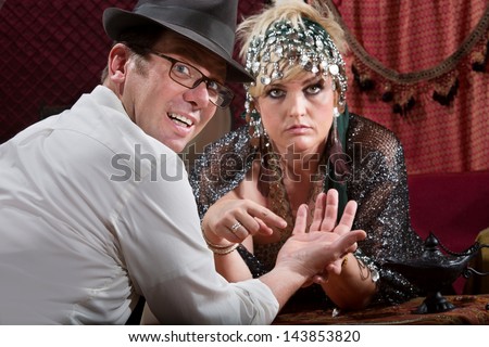 Scared man with fortune teller and evil eye symbol in palm