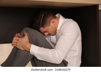 Scared Man Hiding Under Office Desk During Earthquake