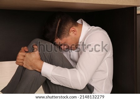 Scared man hiding under office desk during earthquake Foto stock © 