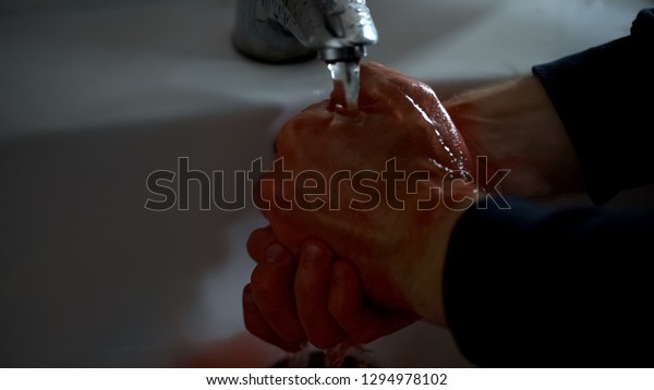 Scared man washing hands in sink after homicide,\
manslaughter, jealousy\
murder