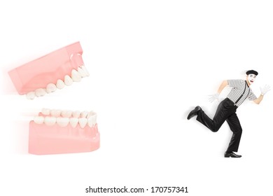 Scared Mime Artist Running Away From An Open Denture, Isolated On White Background