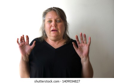 Scared Old Woman With Green Eyes Smiling At Camera. One Beautiful Green Eyed Elder Woman With Panic Attack Concept. Modern Blonde Lady With Casual Hair Isolated On White Wall Background.