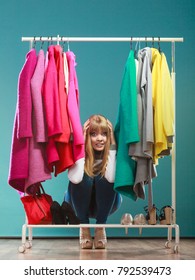 Scared Pretty Woman Hiding Among Clohes In Wardrobe. Attractive Young Girl Customer Shopping In Mall Shop. Fashion Clothing Sale Concept.