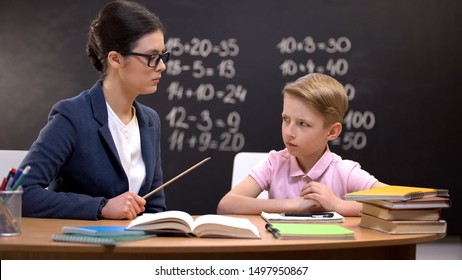 Scared Schoolboy Cautiously Looking At Strict Teacher With Pointer, Education