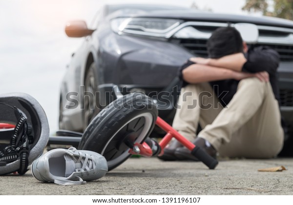 scared and stressed desperate drunken driver\
and bottle of beer in front of automobile crash car with child bike\
after traffic accident in city\
road