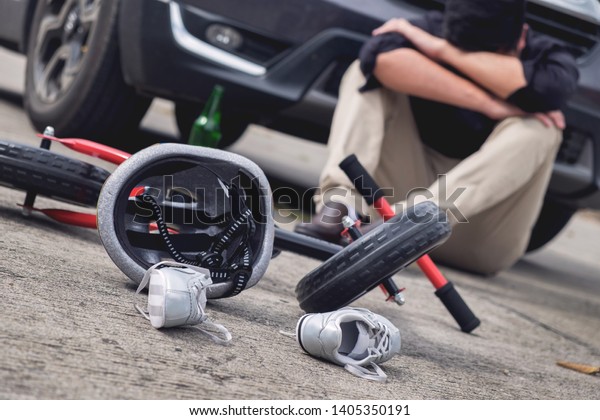 scared and stressed desperate drunken driver\
and bottle of beer in front of automobile crash car with child bike\
after traffic accident in city\
road