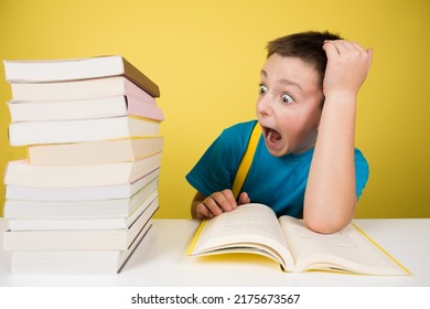 Scared Student Boy Looking At Pile Of Books. Overwhelmed Schoolboy Isolated On Yellow Background.