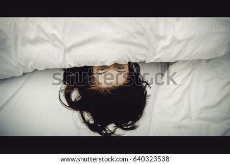 a girl with her hair by her face lying on the bed