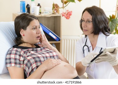 Scared Woman Checking Results On Tablet Computer With Her Doctor