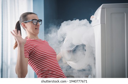 Scared woman dealing with a broken burning appliance at home - Shutterstock ID 1940777671
