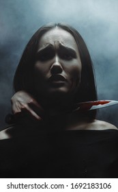 Scared Woman With Hand Holding Bloody Knife By Neck