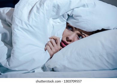 Scared Woman Hiding Behind Blanket In Bedroom At Home