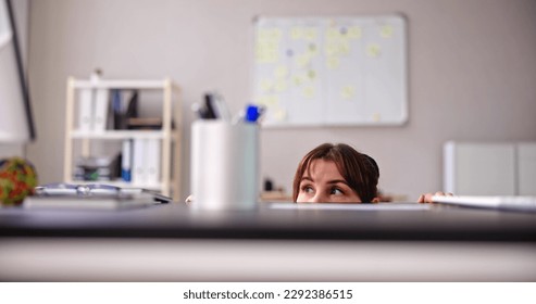 Scared Woman Hiding Behind Chair And Under Desk