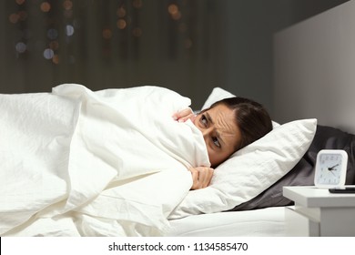 Scared Woman Hiding Under Blanket Lying On A Bed In The Night At Home