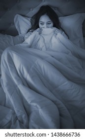 Scared Woman Pulling The Blanket Over Her Head At Night Time.