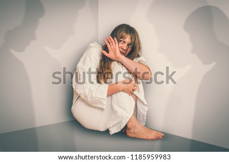 Scared woman with schizophrenia sitting in the corner at room with people shadows - hallucinations and schizophrenia disease concept - retro style