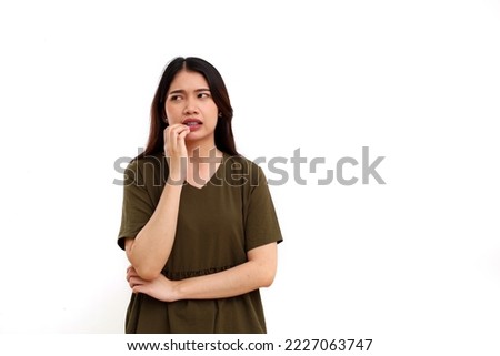 Scared worried young asian woman standing while glancing to sideways. Isolated on white with copyspace