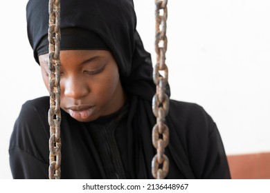 Scared Young African Girl Behind Chains, Symbol Of Domestic Abuse, Child Or Forced Marriage, Gender Disequality