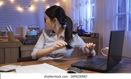 scared young businesswoman turning head around and looking for some strange sound in back while working overtime late in home office.