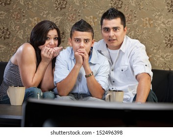 Scared Young Latino Family Watching Television Together