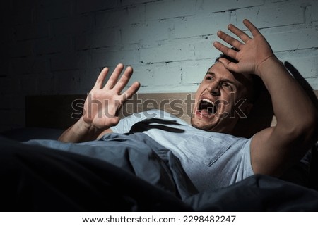 scared young man with ptsd having nightmares and screaming at night