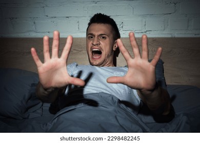 scared young man screaming while having nightmares at night