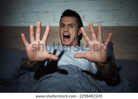 scared young man screaming while having nightmares at night