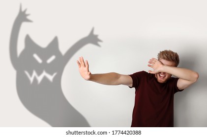 Scared young man suffering from sciophobia  Irrational fear of shadows