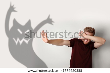 Scared young man suffering from sciophobia  Irrational fear of shadows