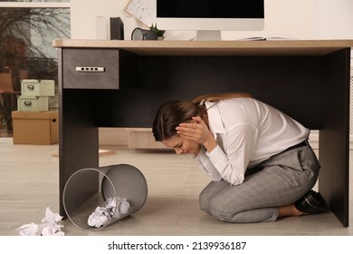 Scared Young Woman Hiding Under Office Desk During Earthquake